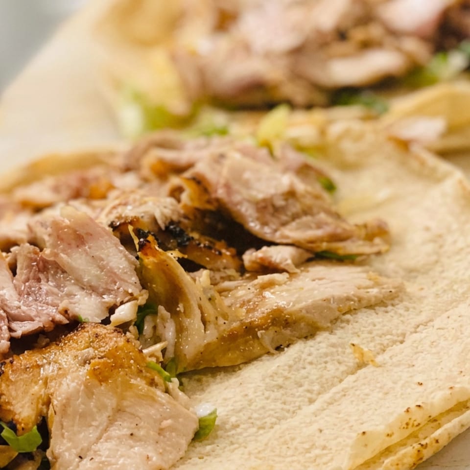 Close-up of grilled chicken shawarma pieces with herbs served on warm flatbread.